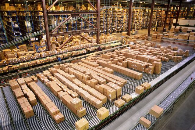 small-orig large industrial distribution warehouse storing products in cardboard boxes on conveyor belts and racks Getty-1091848580